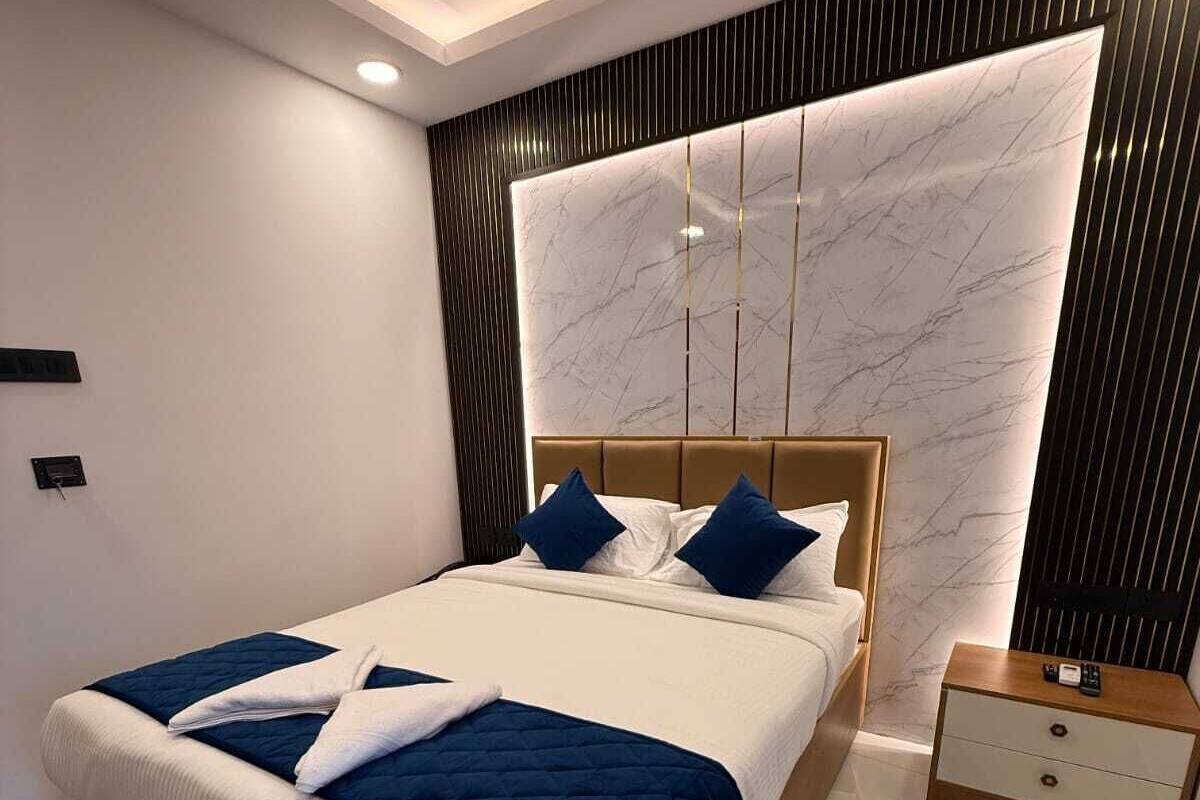 A modern bedroom with a large bed, a nightstand, and a marble-patterned wall.