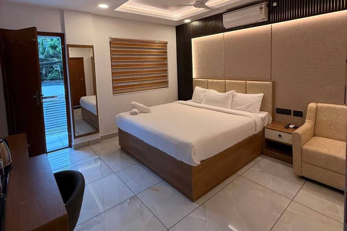 A modern bedroom with a large bed, a bedside table, a chair, and a ceiling fan.