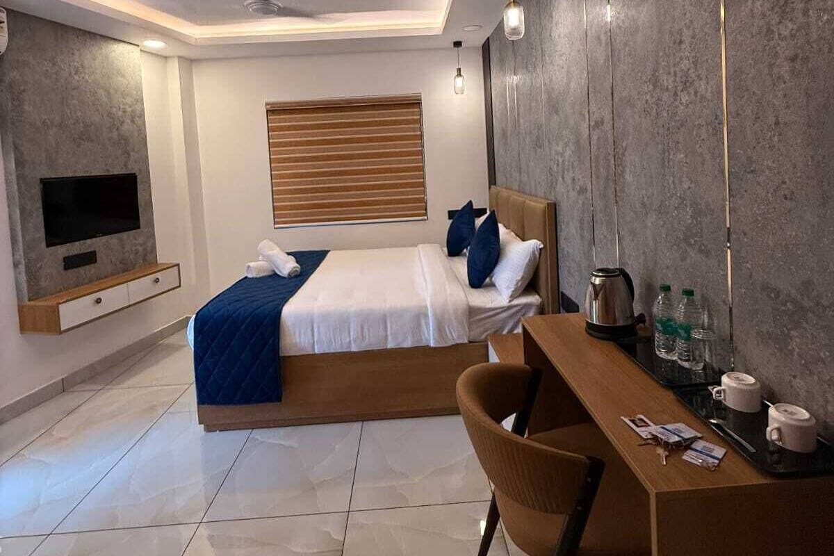 A modern hotel room with a bed, a desk, a chair, a TV, and a ceiling fan.