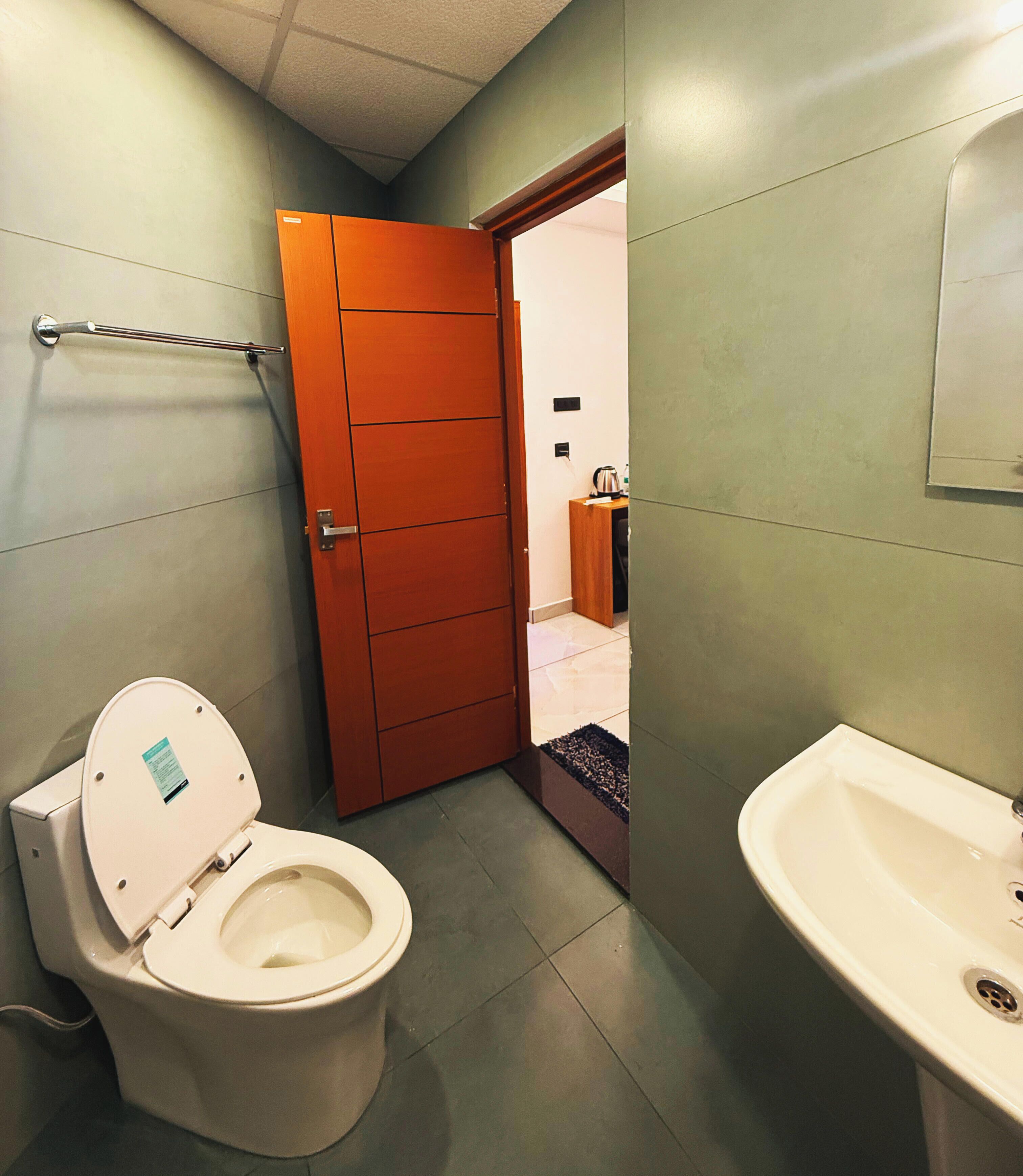 A bathroom with a toilet, a sink, and a door leading to another room.