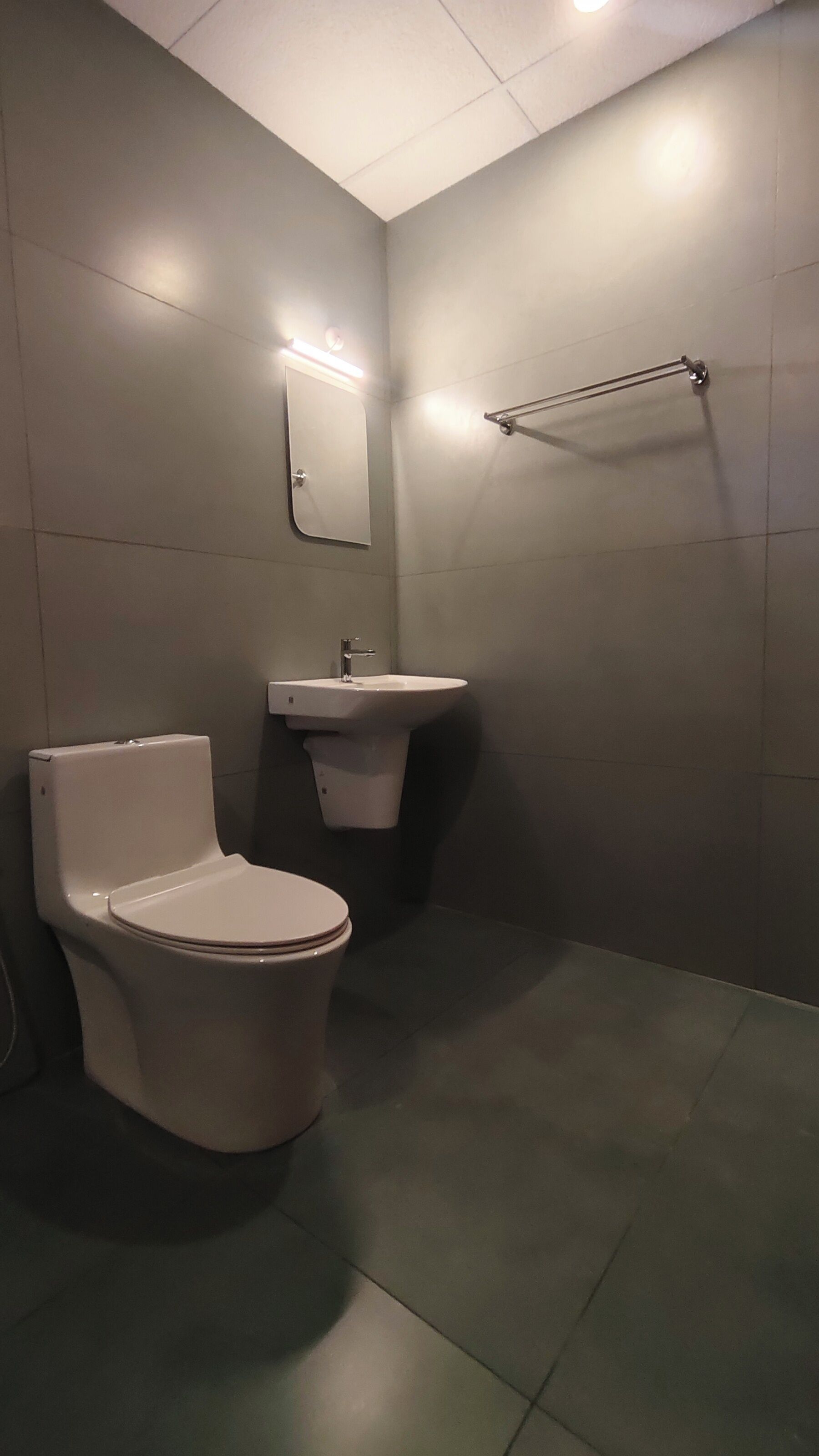 A bathroom with a toilet, sink, and mirror.