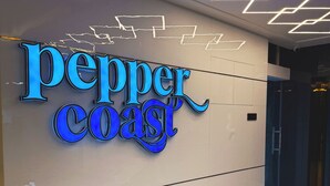 Un interior de hotel moderno con un llamativo letrero que dice 'pepper coast', suelo de mármol y lámparas contemporáneas.