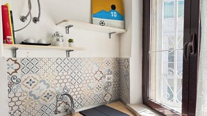 Une cuisine équipée d’un évier, d’une fenêtre donnant sur un paysage agréable et de carreaux décoratifs.