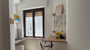 Une cuisine compacte avec une fenêtre, un petit évier et un coin repas équipé d’une chaise.