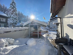 A snow-covered outdoor area with a small shelter, a bench, and a flag.