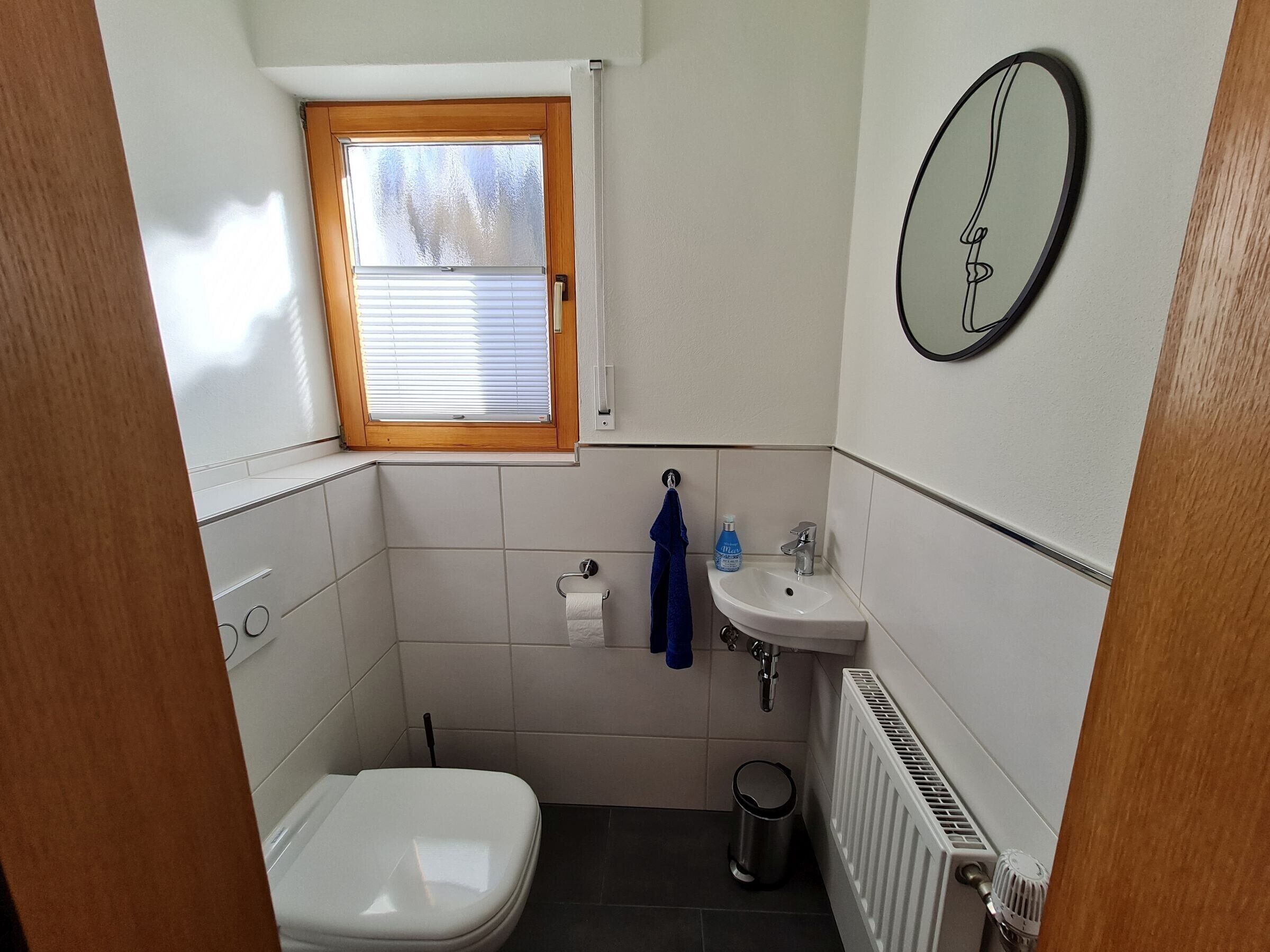 Ein kleines Badezimmer mit Toilette, Waschbecken und Fenster.