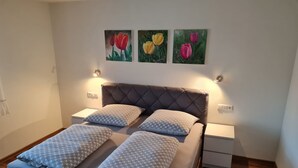 Une chambre à coucher avec un lit, deux tables de chevet et trois tableaux accrochés au mur.