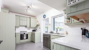 Een keuken met lichtgroene kastjes, roestvrijstalen apparatuur en een wit aanrecht.