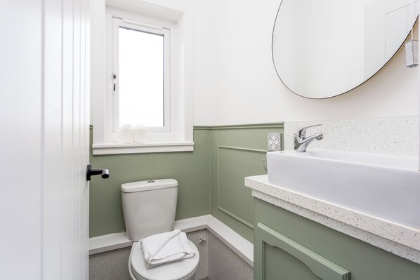 A bathroom with a toilet, sink, and mirror.