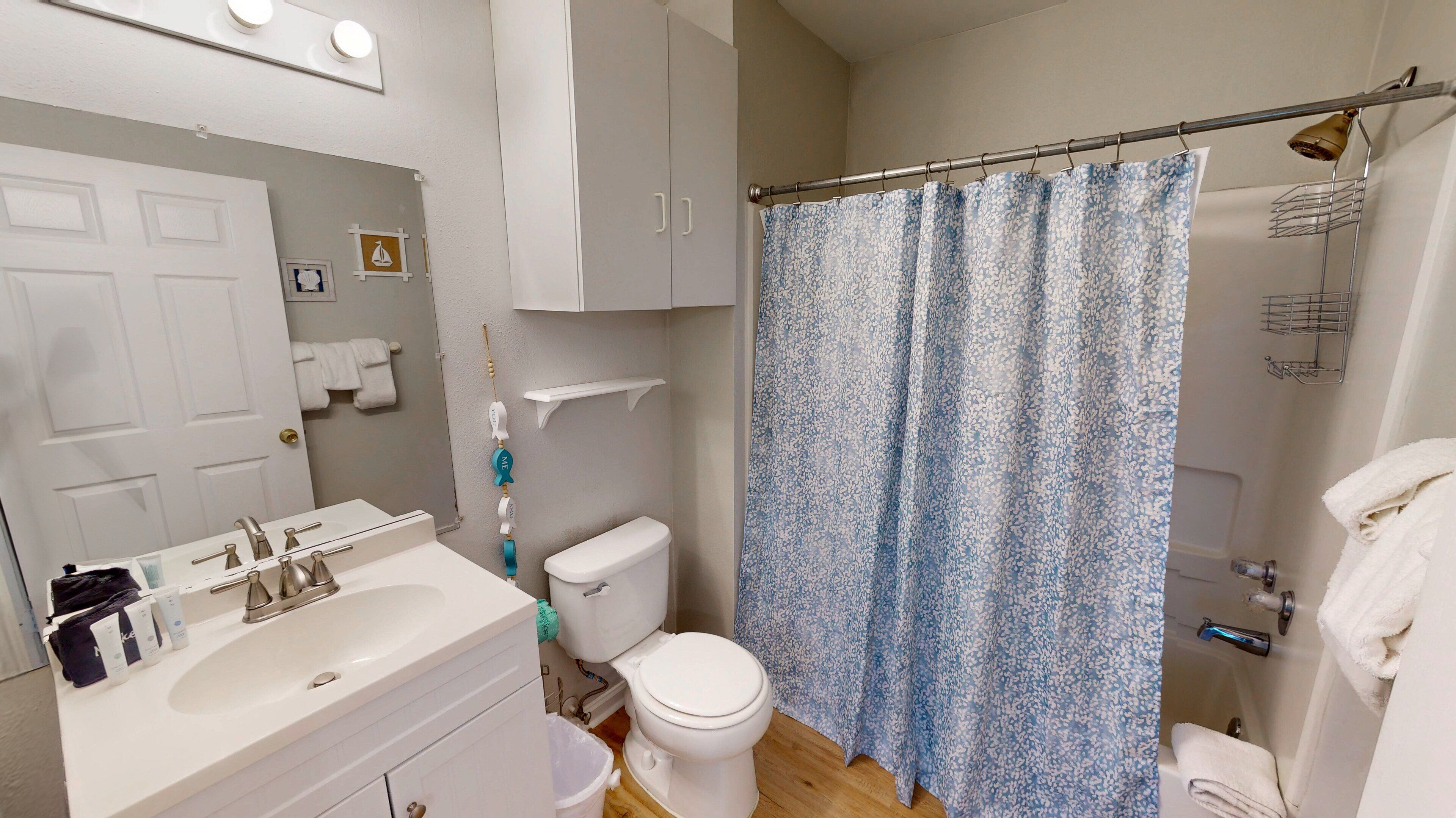 A bathroom with a white sink, toilet, and shower curtain.