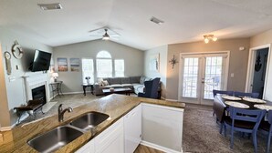 A spacious kitchen with a dining area, a fireplace, and a ceiling fan. - Charming 2BR Condo w/ Private Balcony in Gulf Shores, Pool, Hot Tub (Gulf Shores)