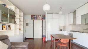 Una cocina moderna con armarios blancos, una mesa de comedor con sillas y un sofá en la sala de estar.
