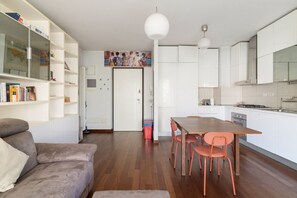 Une cuisine moderne avec des meubles blancs, une table à manger avec des chaises et un canapé dans l’espace salon.