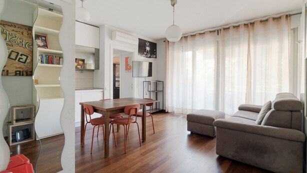 Una sala moderna con una mesa de comedor de madera, un sofá y un televisor.