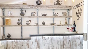 A rustic bar area with shelves of various tea pots and a wine bottle. - Honeysuckle Cottage (Swaffham)