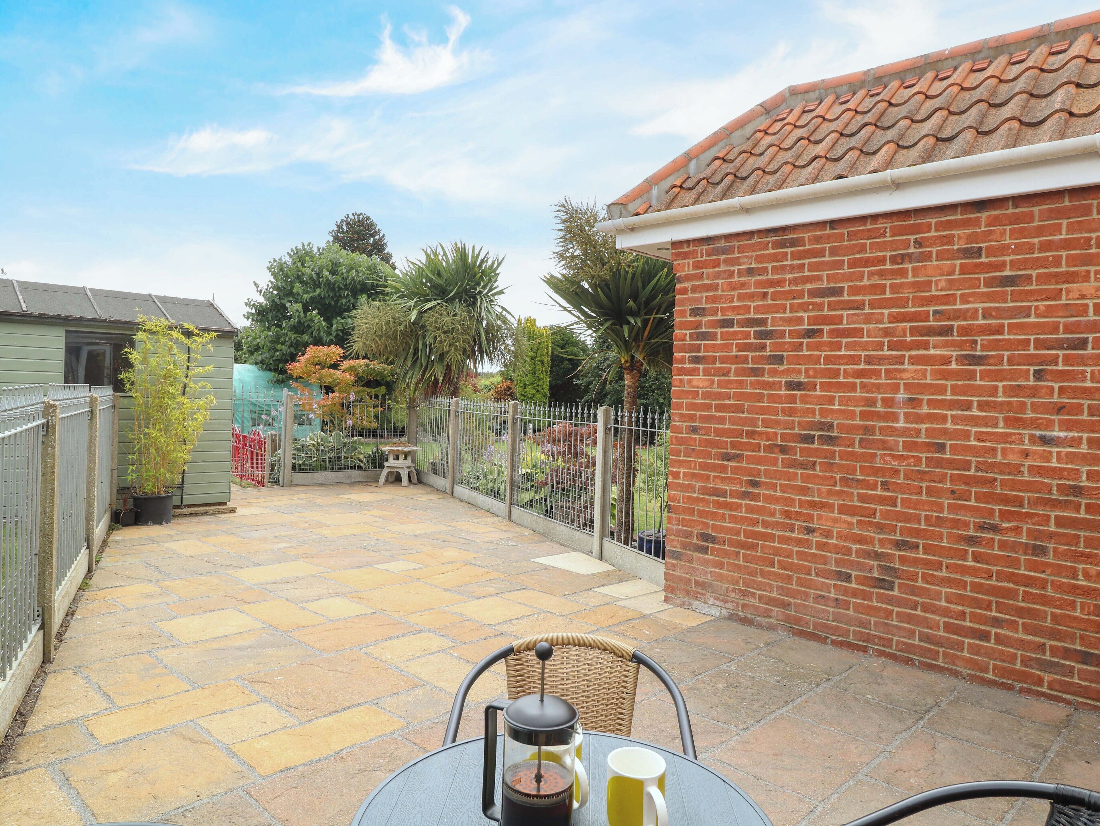 A patio with a table and chairs, a coffee maker, and a potted plant.