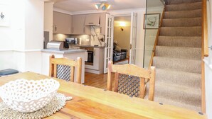 A compact living space with a kitchen, dining area, and a staircase. - Honeysuckle Cottage (Swaffham)