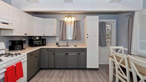 A compact kitchen with white cabinets, a stove, a microwave, and a sink. - Game On Getaway: Slide & Sleeps 6 (Big Bear Lake)