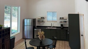 Een moderne keuken met houten balken in het plafond, een roestvrijstalen koelkast, een spoelbak en een eetgedeelte met een ronde tafel en stoelen.
