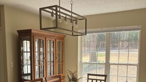 A dining room with a wooden table, chairs, a glass cabinet, and a hanging light fixture. - Delightful 3-bedroom, 2 bath home in Savannah Lakes Village--McCormick, SC (McCormick)