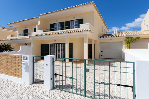 A two-story residential building with a gated entrance, a garage, and a paved driveway. - Spacious Villa - Walk to Beach & City Center (Lagos)