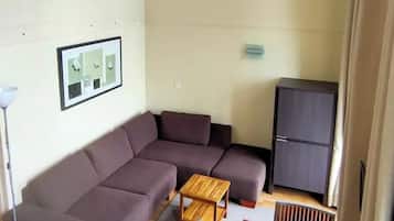 Een woonkamer met een bruine bank, een houten tafel en een blauwe stoel.