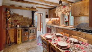 A rustic kitchen with wooden beams, stone walls, and vintage appliances.