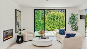 A modern living room with a white sofa, a round coffee table, and a fireplace.