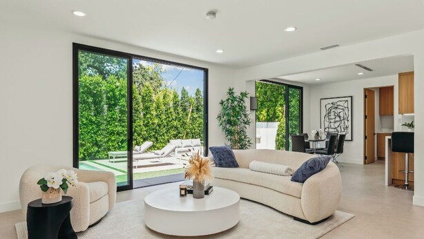A modern living room with a large window, a round coffee table, and a beige sofa.