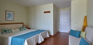 Habitación de hotel con una cama grande, un sofá, una puerta y un cuadro en la pared.