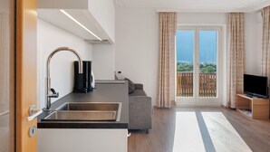 A modern kitchen with a sink, a coffee machine, and a flat-screen TV.