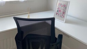 A black mesh office chair with a white desk and a framed floral artwork on the wall. - Sherwood Hideaway Retreat (Nottingham)
