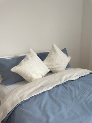 A bed with a blue and white duvet, two white pillows, and a blue pillow. - Sherwood Hideaway Retreat (Nottingham)