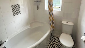 Een badkamer met een vrijstaand bad, een toilet en een douche.