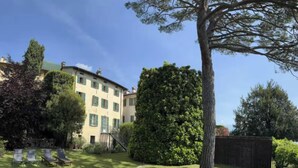 Ein Gebäude mit Garten, einem großen Baum und einer Umzäunung.
