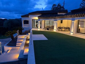 Una casa moderna con patio, mobiliario exterior e ingreso bien iluminado.