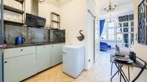 Eine kleine Küche mit Kühlschrank, Kaffeemaschine und einem Essbereich mit Tisch und Stühlen.