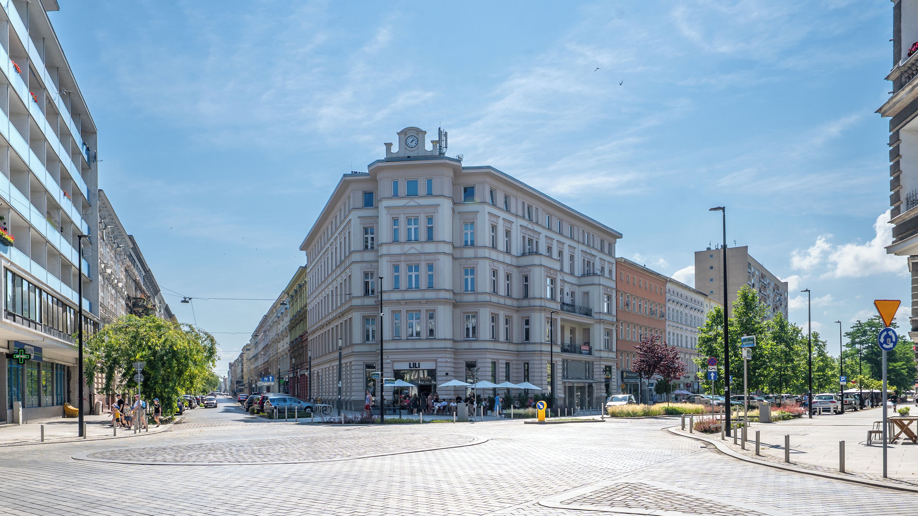 Un bâtiment historique doté d’une tour horlogée, de grandes fenêtres et d’une place pavée.