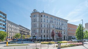 Ein mehrstöckiges Gebäude im klassischen Stil, mit einem zentralen Eingang und einem Vordach.
