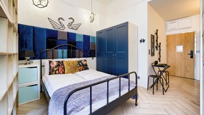 Un dormitorio moderno con una cama, mesitas de noche, un armario y un pequeño rincón de descanso.