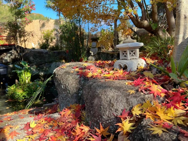 A stone lantern surrounded by autumn leaves on a rock.