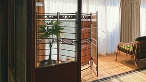 Een traditionele Japanse kamer met tatami vloeren, een shoji scherm, een lage tafel van tatami matten, een groene fauteuil en een bamboe plant.