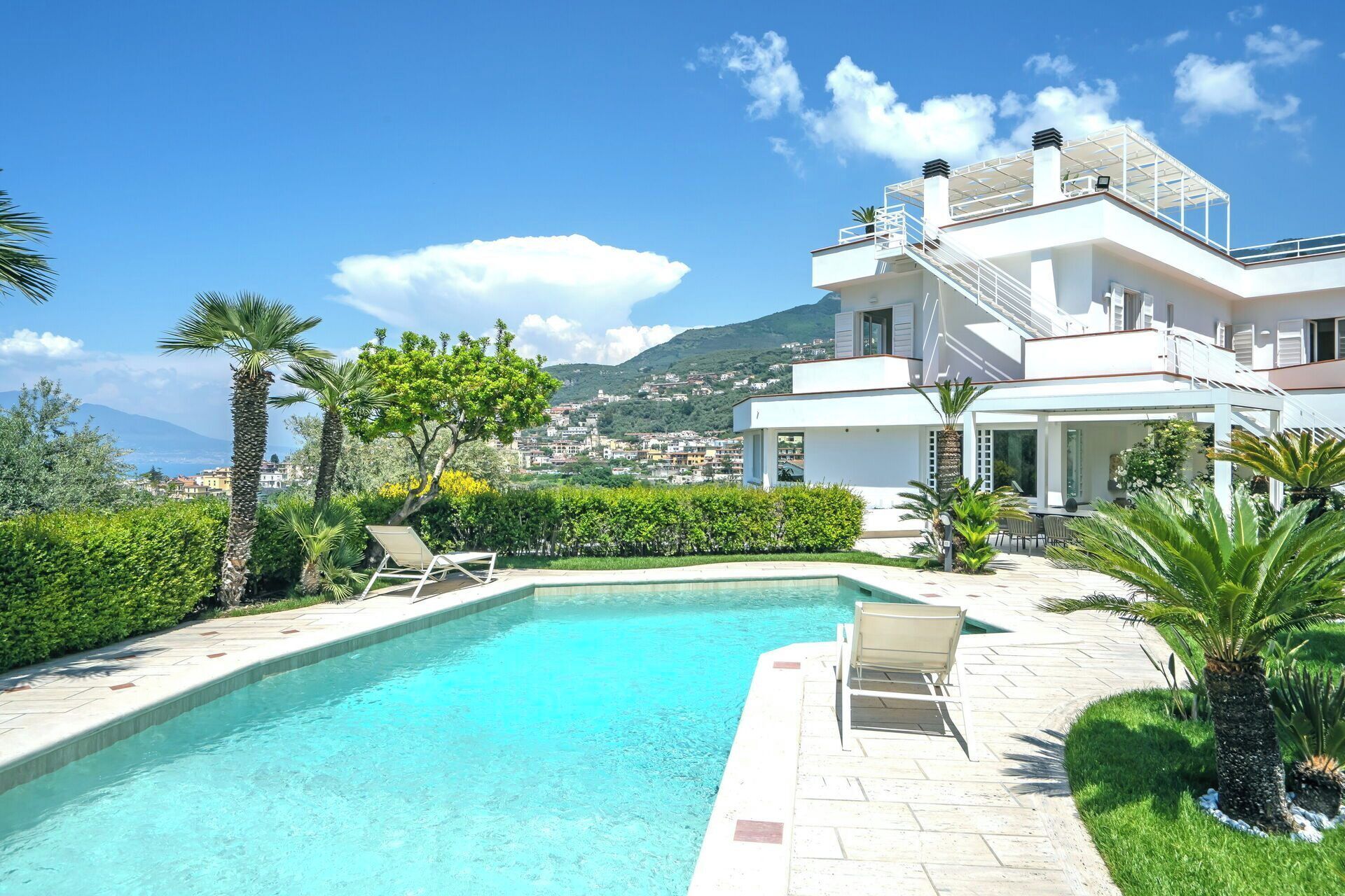 Una villa moderna con piscina, abundante vegetación y vistas panorámicas a la montaña.