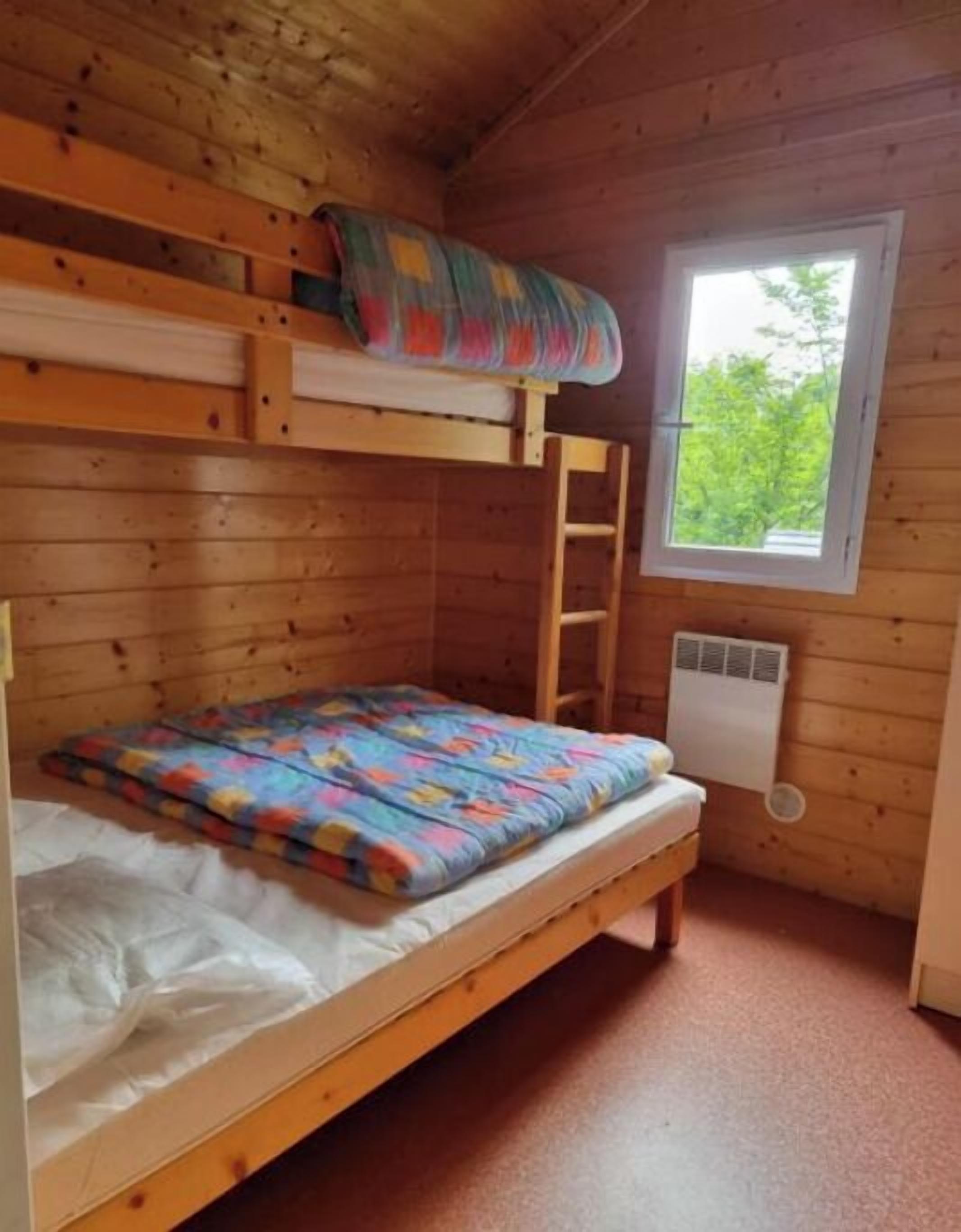 A bunk bed room with a window and a ladder.