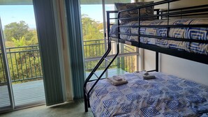 A room with a bunk bed, a window with curtains, and a view of greenery outside. - Enjoy Sydney's Northern Beaches. Unique district views, 1950s classic, sleeps 5 (Seaforth)