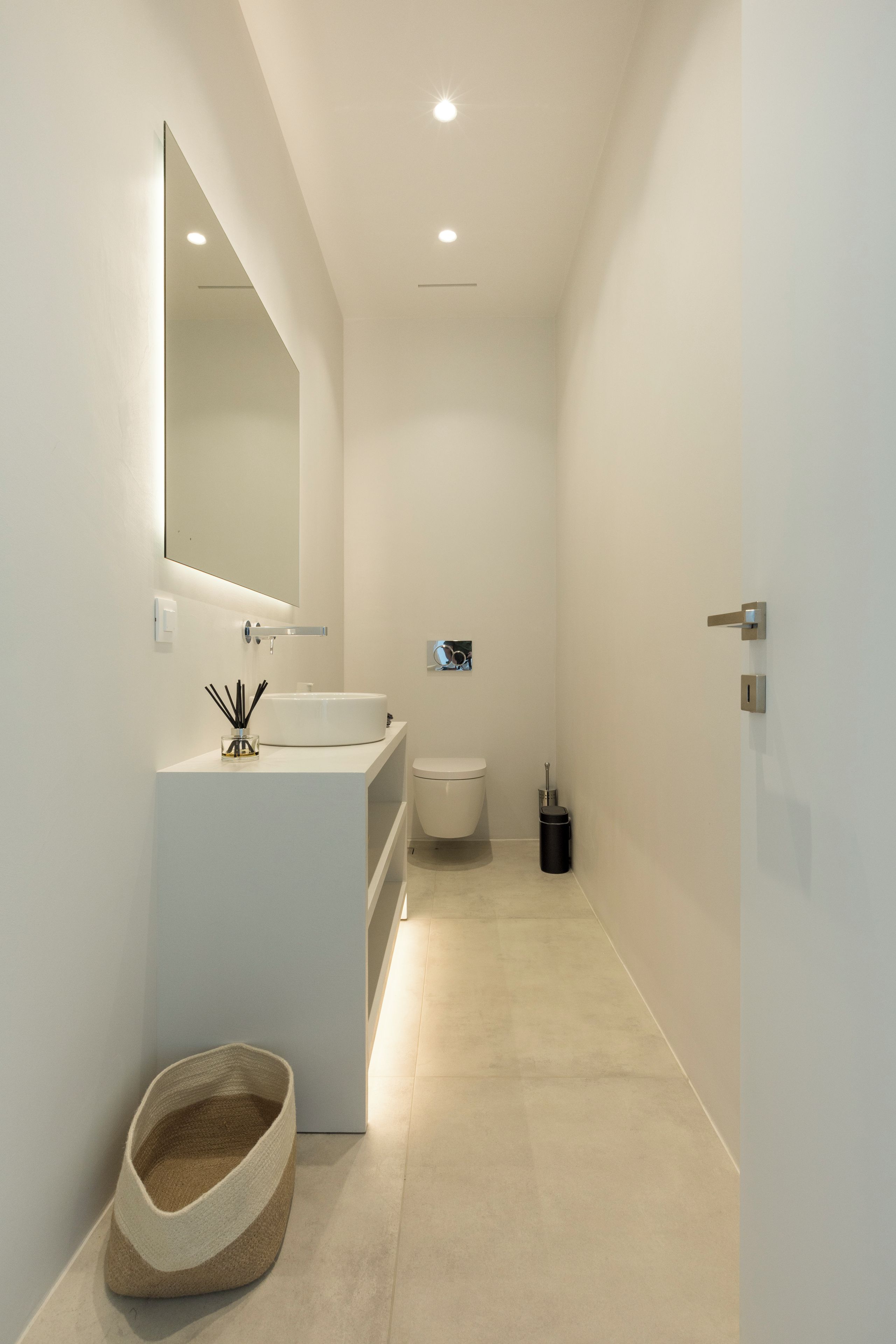 Een moderne badkamer met een wit wastafelmeubel, spiegel en toilet.