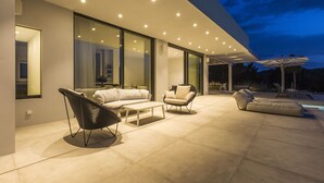 An outdoor living area with modern furniture, a pool, and a covered patio.