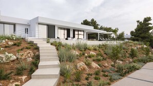 A modern house with a staircase leading to a covered outdoor area with seating.
