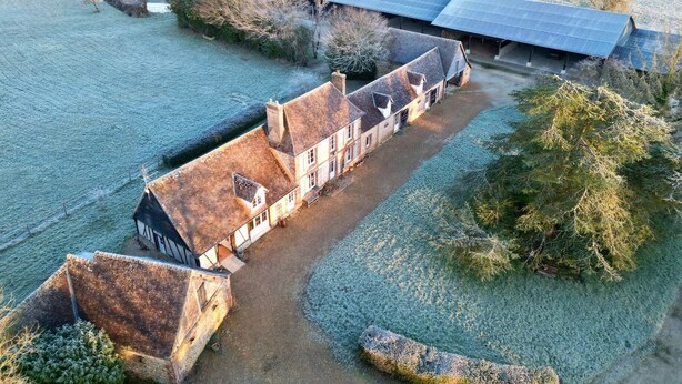 A large, traditional stone building with a long driveway leading to a covered carriage area.