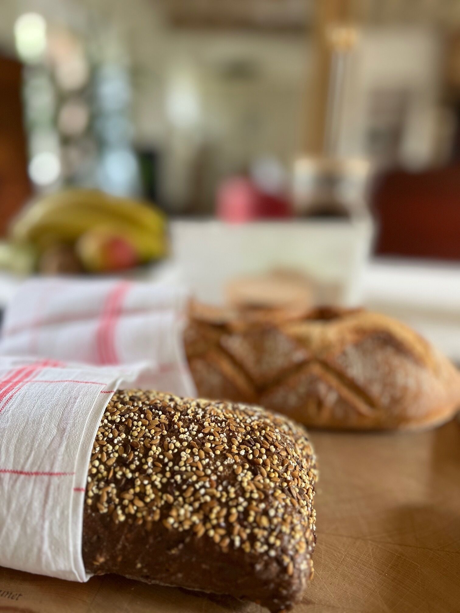 Una hogaza de pan con semillas sobre una mesa de madera, con un fondo desenfocado.